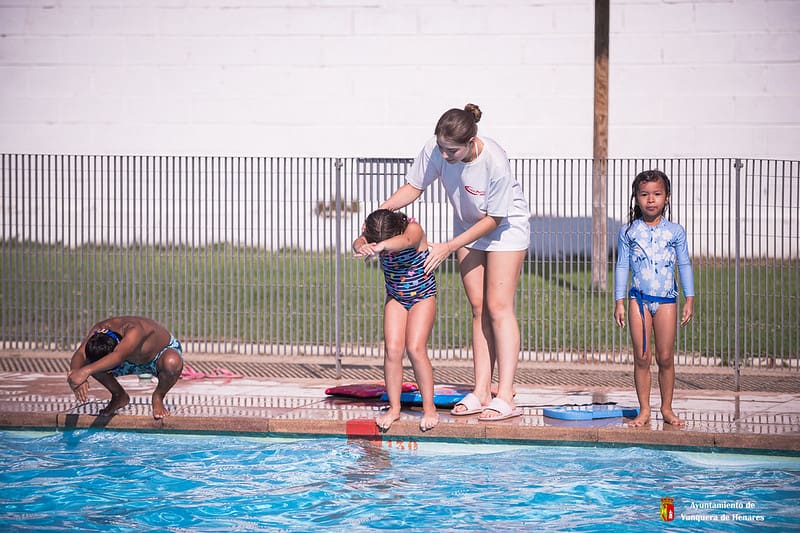 Cerca de una veintena de niños y niñas disfrutan y aprenden en el curso de natación
